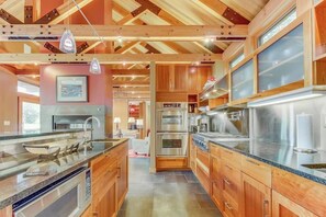 A modern kitchen with wooden cabinets, stainless steel appliances, and pendant lighting. - Spacious 3BR Oceanfront - Chef's Kitchen (Anacortes)