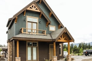 A two-story house with a balcony, stone foundation, and a garage. - Spacious 4BR Waterview Suncadia Resort (Cle Elum)