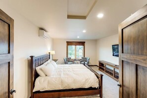 A bedroom with a large bed, a desk, two chairs, a television, and a window. - Spacious 4BR Waterview Suncadia Resort (Cle Elum)