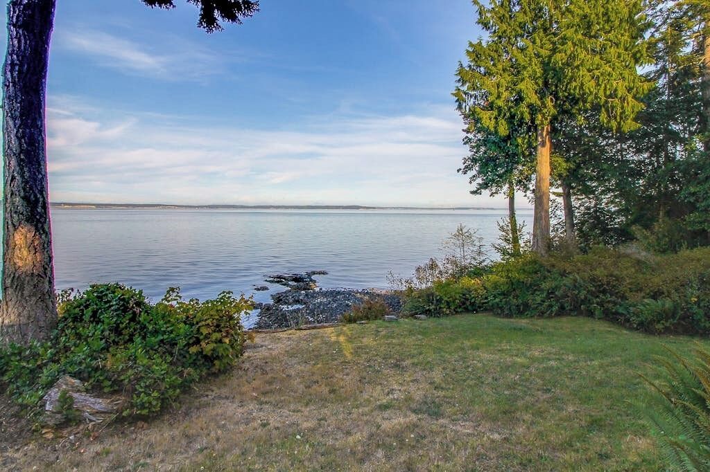 A natural landscape with a body of water, trees, and a grassy area.