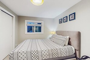 A bedroom with a bed, a window, and wall-mounted pictures.