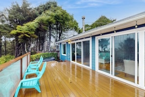 A wooden deck with outdoor seating and a covered area with sliding glass doors.