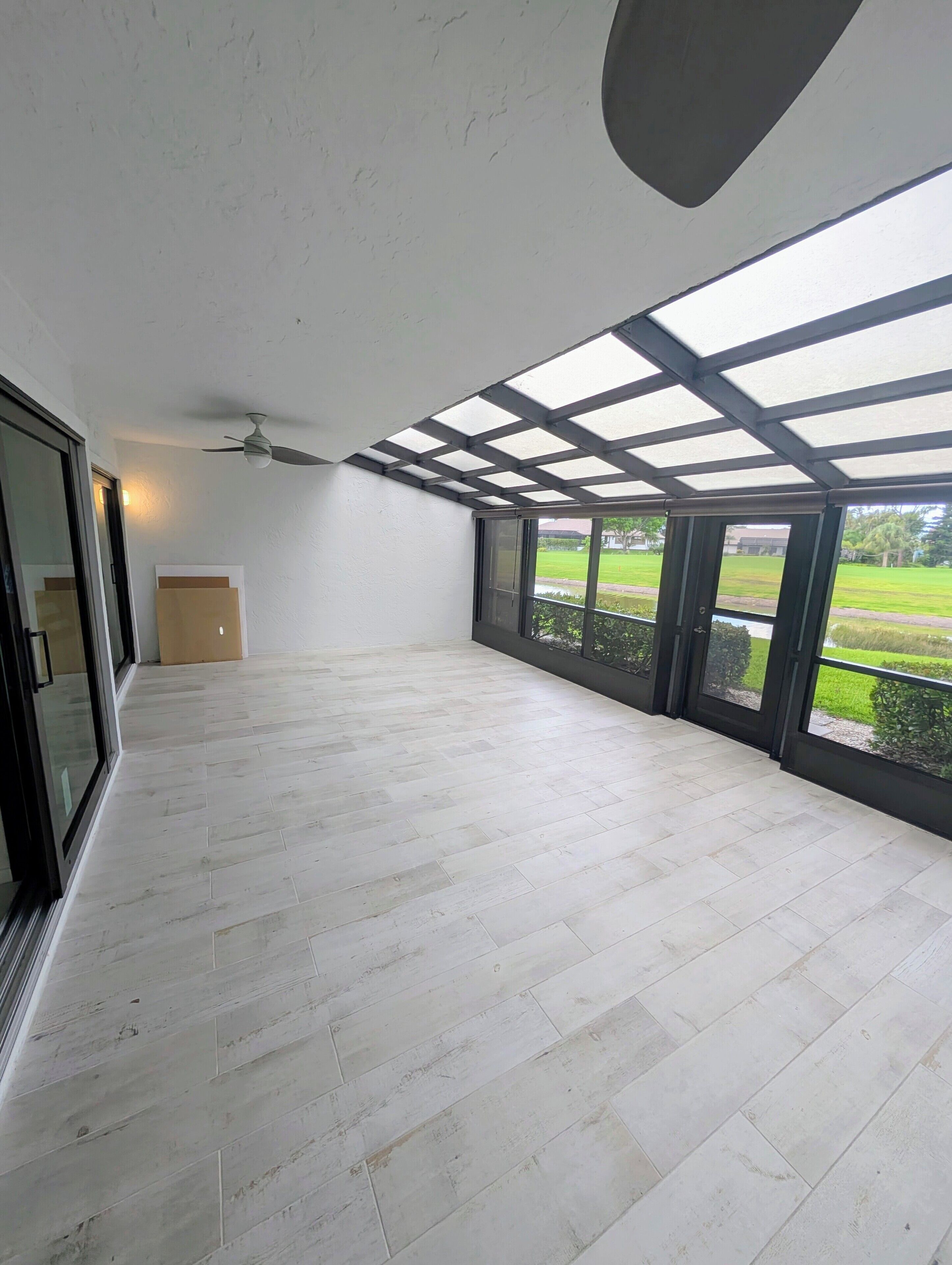 Una habitación amplia con techo alto, ventanas grandes y ventilador de techo.