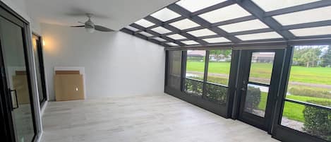 Una habitación amplia con techo alto, ventanas grandes y ventilador de techo.