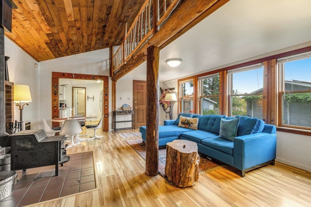 Ein geräumiger Wohnbereich mit blauem Sofa, Holzboden und großen Fenstern.