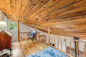 Une pièce avec un plafond en bois, une chaise, une table et une fenêtre.