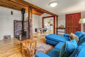 Ein Wohnzimmer mit einem blauen Sofa, einem Holztisch und einem Kamin aus Backsteinen.