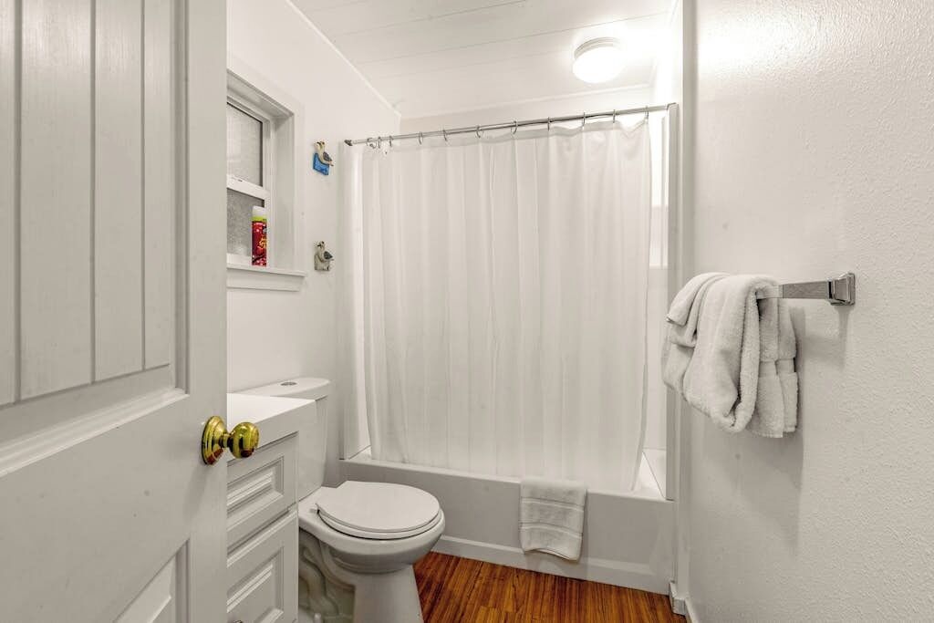 Et badeværelse med toilet, vask og bruseforhæng.