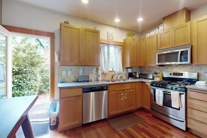 A modern kitchen with wooden cabinets, stainless steel appliances, and a view to the outside. - Walkable 2BR Dog Friendly - Fireplace (Seattle)