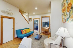 A modern living room with a sofa, a coffee table, a lamp, and a painting on the wall. - 2 BR townhome with gas fireplace and backyard (Seattle)