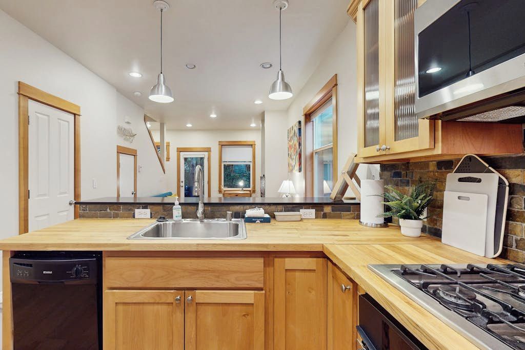 A modern kitchen with wooden cabinets, a stainless steel sink, and a built-in stove.