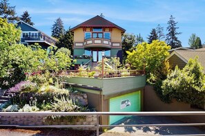 A two-story house with a balcony, surrounded by lush greenery and trees. - 2BR Sun-Drenched Guesthouse - Cruise (Seattle)