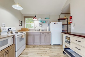 Una cocina con estufa, microondas, lavaplatos y refrigerador.