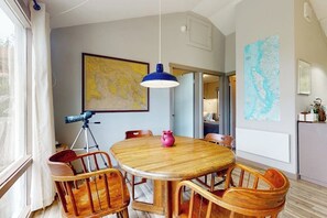 A dining area with a wooden table and chairs, a blue pendant light, and a map on the wall. - 2BR family friendly getaway with deck and bay view (Anacortes)