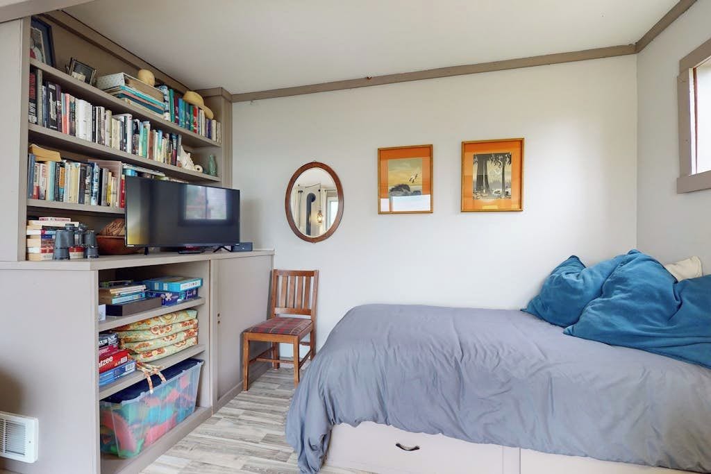 Une chambre à coucher avec un lit, une télévision, une bibliothèque et une chaise.