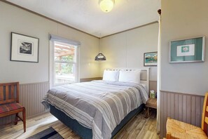 Une chambre à coucher comprenant un lit, une chaise, une fenêtre et des œuvres d’art accrochées au mur.