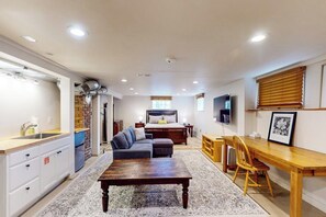 A modern living space with a kitchen, dining area, and a bedroom with a large bed and a TV. - Charming, dog-friendly 3BR with terrace (Seattle)
