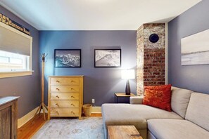 A room with a grey sofa, a wooden dresser, and two framed pictures on the wall. - Charming, dog-friendly 3BR with terrace (Seattle)