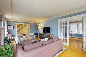A living room with a sofa, a television, and a staircase leading to another room. - Charming, dog-friendly 3BR with terrace (Seattle)