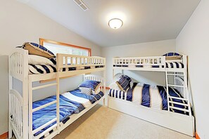 A room with bunk beds, a window with blinds, and a ceiling light.
