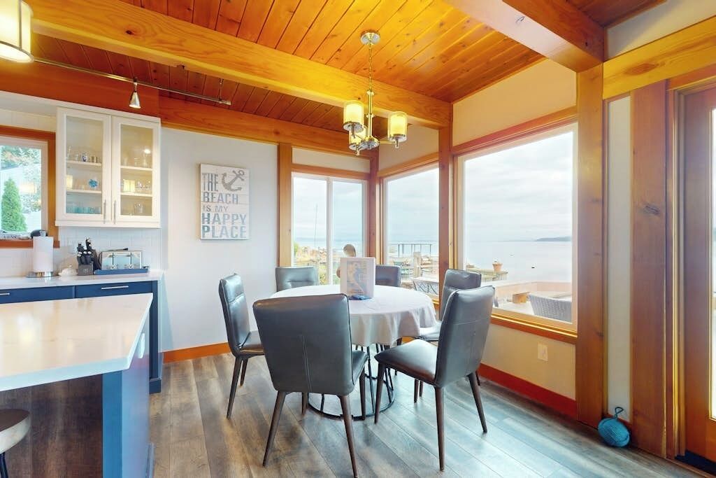 Een eetruimte met een ronde tafel, stoelen en uitzicht op de oceaan.
