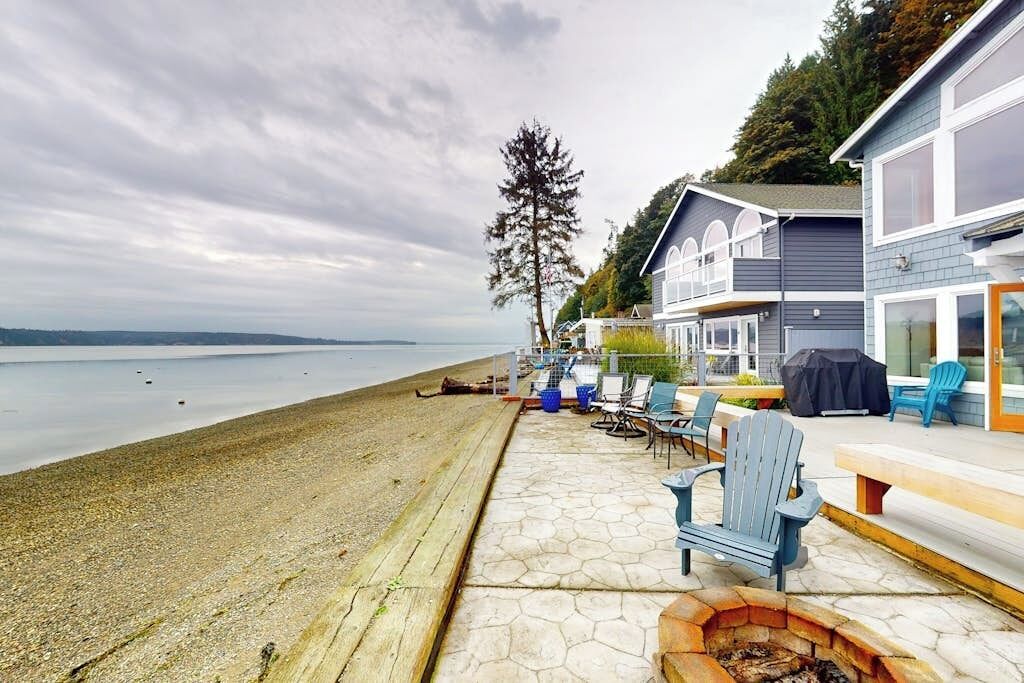 A waterfront property with a patio area featuring outdoor seating and a fire pit.