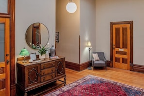 A room with a wooden dresser, a mirror, a lamp, a chair, and a patterned rug.