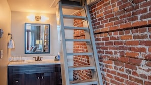 Une salle de bain avec un meuble-lavabo en bois foncé, un miroir et un mur en briques.
