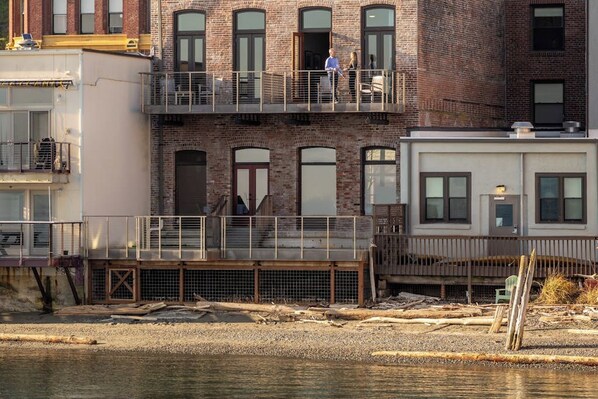 A multi-story building with a brick facade, balconies, and a waterfront view.