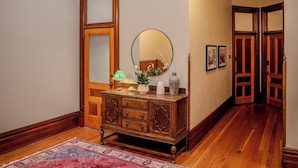 Un couloir doté d’un plancher en bois, d’un grand miroir, d’une armoire en bois et d’un tapis à motifs.