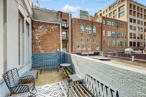 Eine Dachterrasse mit Backsteinmauer, blauem Geländer und einem Tisch mit Stühlen.