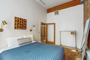Une chambre à coucher avec un lit, deux lampes de chevet, un plafond en bois, une porte et un radiateur.