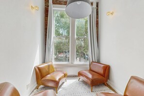 Une pièce avec deux fauteuils en cuir, un luminaire blanc au plafond et une fenêtre avec des rideaux.