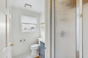 Un bagno con il water, una finestra e una porta.