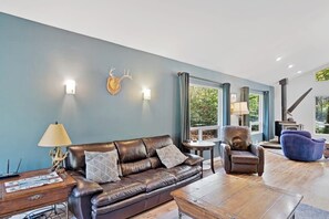 A living room with a brown leather sofa, a blue armchair, and a wooden coffee table.