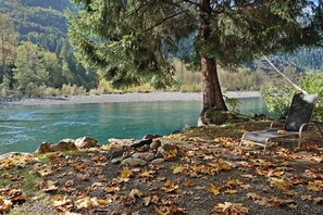 A lakeside view with a chair and a tree.