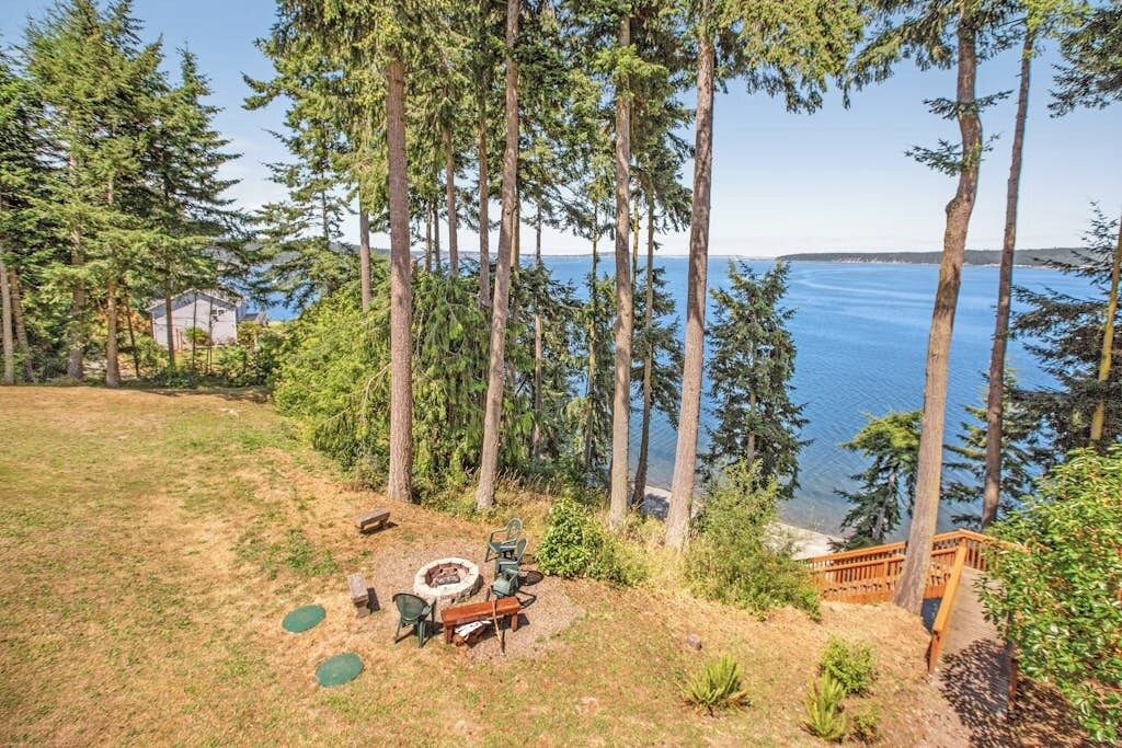 A backyard with a fire pit, seating, and a view of the ocean.