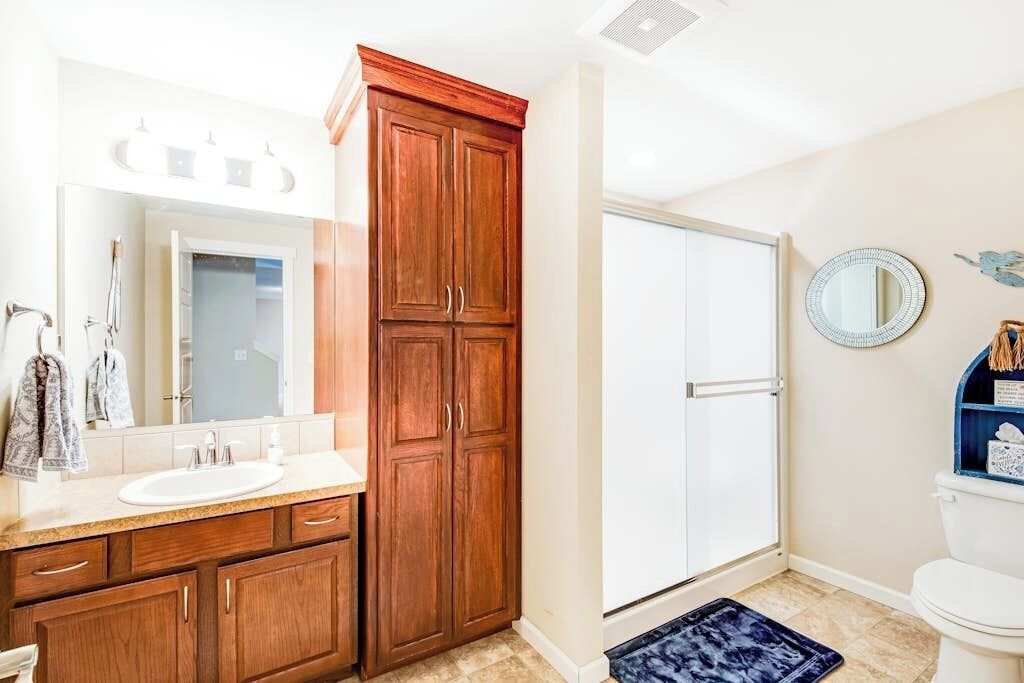 Une salle de bain avec un meuble-lavabo en bois, un évier, un miroir et des toilettes.