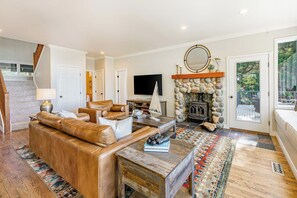 A living room with a fireplace, leather sofa, and a television. - Stunning 5BR Oceanview Birch Bay Dog Friendly (Blaine)