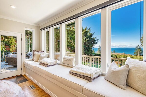 A sunlit room with a large window overlooking a scenic view of trees and a body of water. - Stunning 5BR Oceanview Birch Bay Dog Friendly (Blaine)