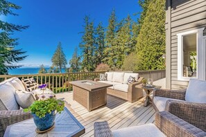 A deck with wicker furniture, a glass-top table, and a potted plant. - Stunning 5BR Oceanview Birch Bay Dog Friendly (Blaine)