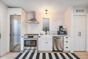 A modern kitchen with white cabinetry, stainless steel appliances, a gas stove, a microwave, and a dishwasher. - 1BR All-New - Central AC - Full Kitchen (Seattle)