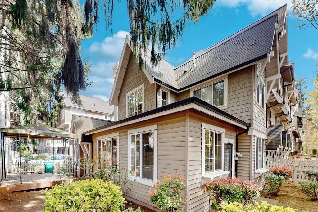 A two-story house with a covered patio, a fenced yard, and a clear sky.