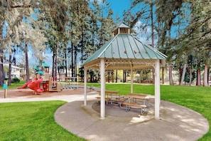 A park with a gazebo, picnic tables, and a playground. - Bright 2BR with deck, office & central location (Redmond)