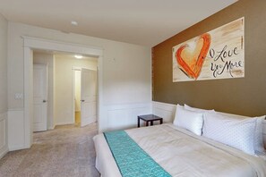 A bedroom with a bed, a nightstand, a wall art piece, and a door leading to another room. - Bright 2BR with deck, office & central location (Redmond)