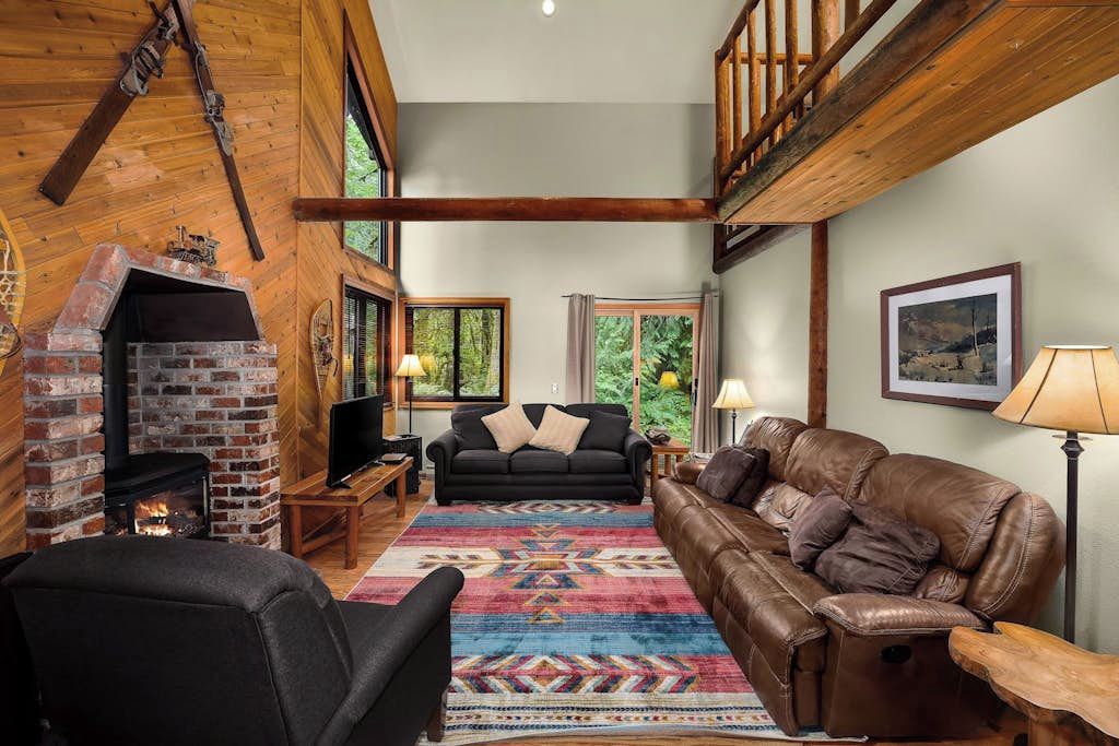 Una sala de estar acogedora con chimenea, sofá de cuero y alfombra colorida.