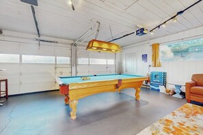 Een pooltafel in een kamer met witte wanden en een groot raam.