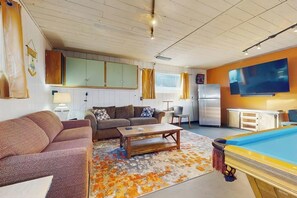 Een woonkamer met een bank, salontafel en een pooltafel.