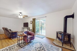Ein Wohnzimmer mit Sofa, Sessel, Tisch, Kamin und Deckenventilator.