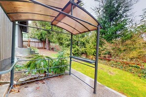 Un espace extérieur abrité, doté de rampes en métal et d’un banc.